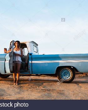 portrait-of-young-female-surfer-leaning-on-pick-up-truck-door-leucadia-E8AMY8