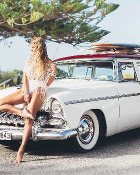 Portia-leaning-against-classic-surf-car-with-surfboard-on-roof